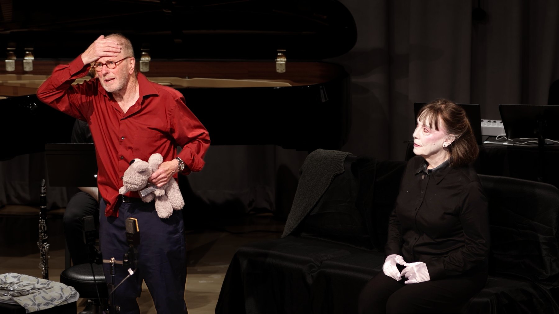 Mr. K and the AI caregiver figure on stage, holding a worn teddy bear